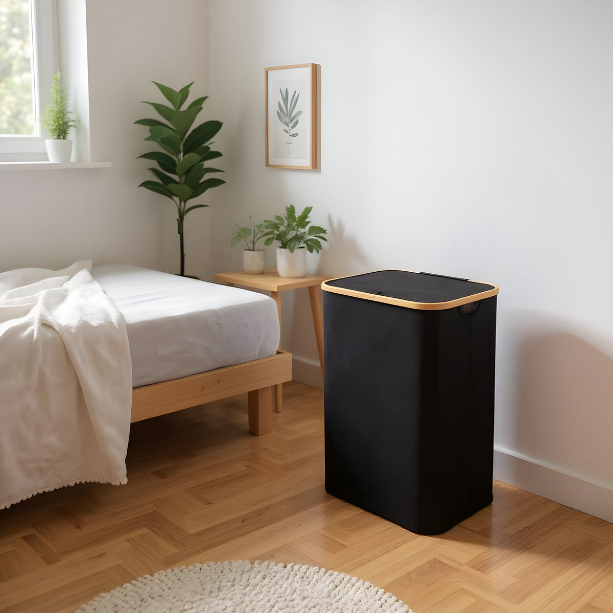 Black large laundry hamper with lid beside a bedroom bed