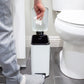 Slim white step trash can fitting beside a bathroom toilet